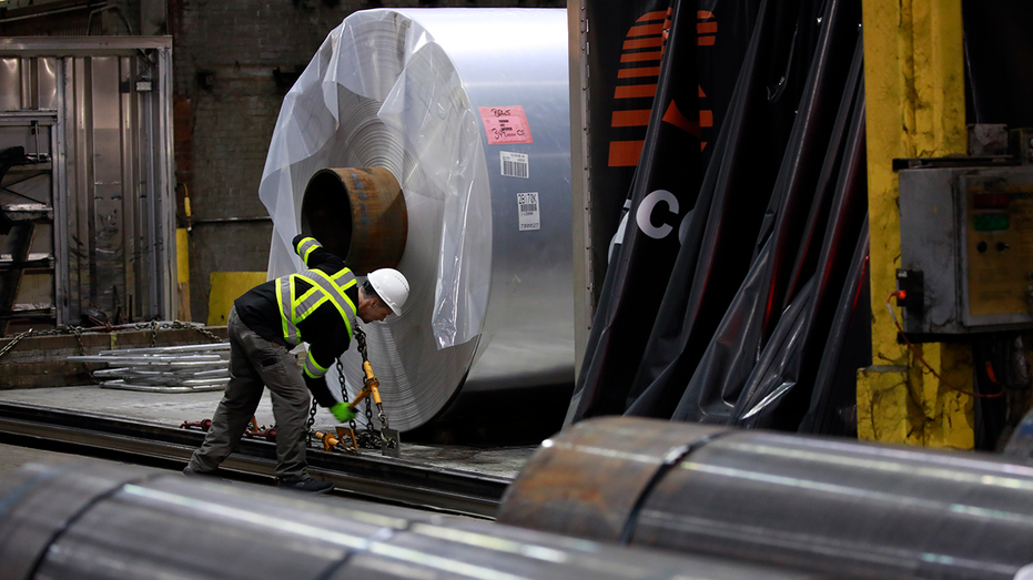 Worker loading coil onto truck.