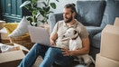 A man uses his laptop computer in his new apartment, accompanied by his dog. - Fox Business News