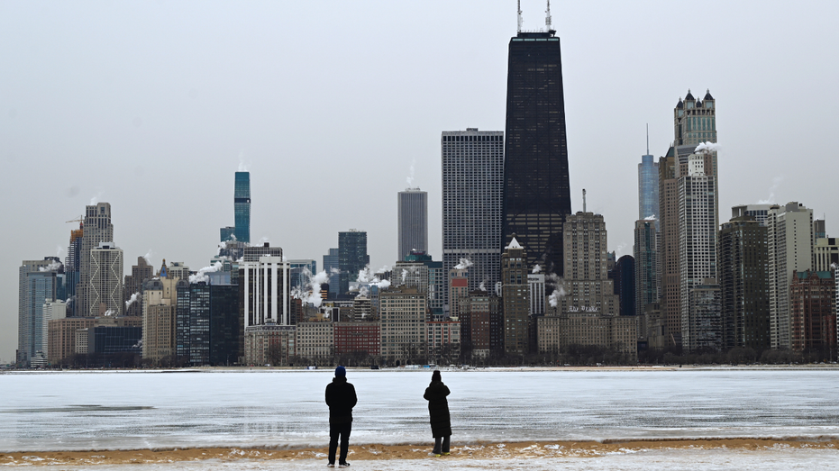 People are seen taking a photo of the Chicago skyline.