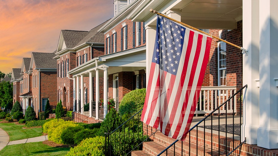 US flags hang from brick homes at sunset