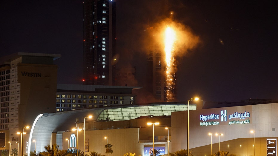 Smoke rises from a burning building hit by an Iranian drone strike in Manama