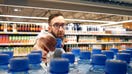 A shopper takes a plastic water bottle off a shelf at a grocery store. - Fox Business News