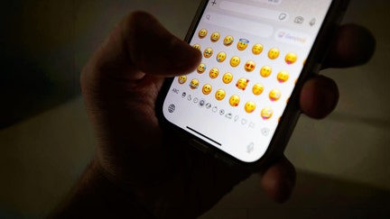 A person taps an emoji on an Apple iPhone. - Fox Business News