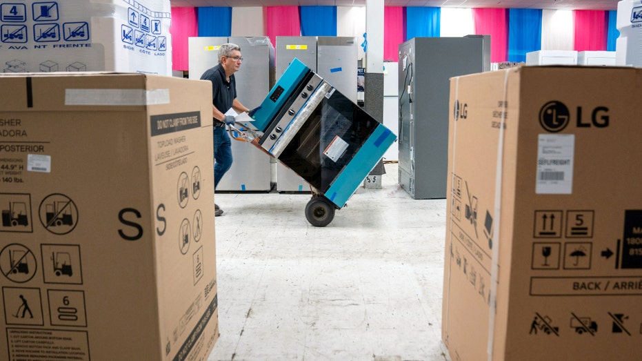 A worker pushes an oven in a store.