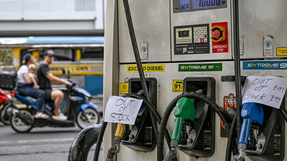 Notices indicating fuel shortages hang on pumps at a Manila gas station as global oil markets spike due to conflict-related supply fears.
