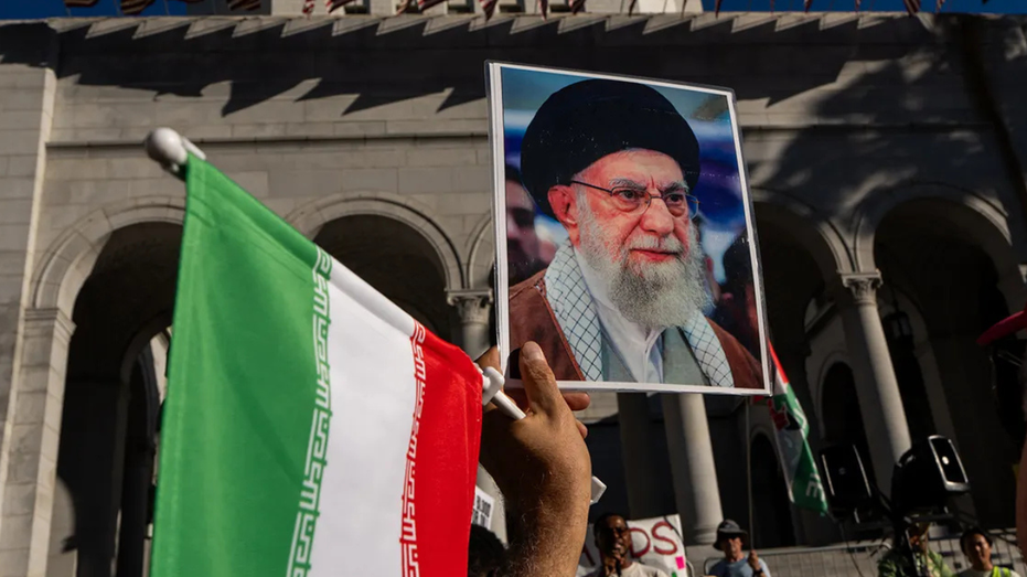 A protester raises the Iranian flag and a photo of Iran's Supreme Leader Ayatollah Ali Khamenei.