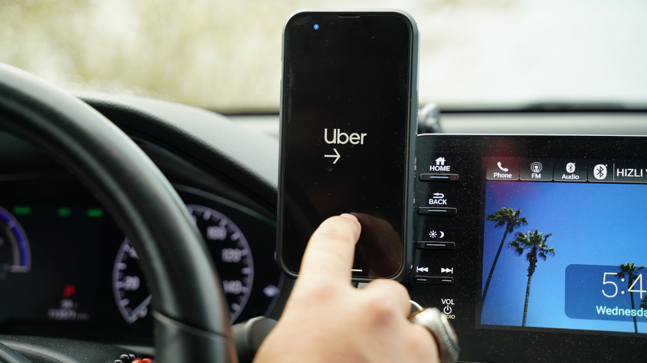An Uber driver is seen operating the app from a cell phone.
