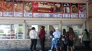 Customers wait in line to order below signage for the Costco Kirkland Signature $1.50 hot dog and soda combo, which has maintained the same price since 1985 despite consumer price increases and inflation, at a food court outside a Costco Wholesale warehouse store in Hawthorne, California on August 27, 2025.  - Fox Business News