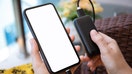 A person holds a smartphone connected to a portable power bank charger. - Fox Business News