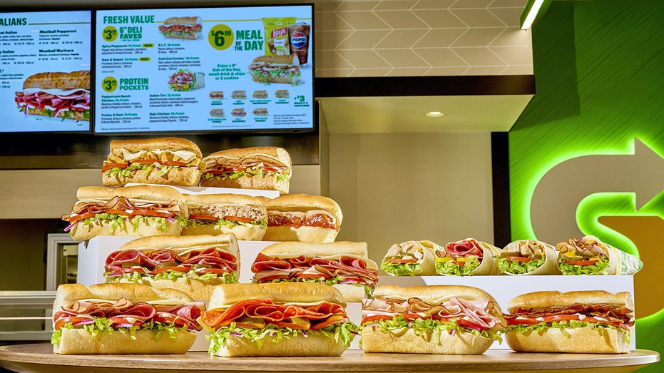 Subway sandwiches in front of a menu.