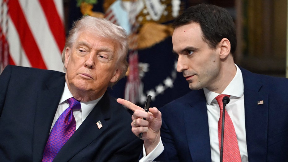 Michael Kratsios points while sitting next to Donald Trump