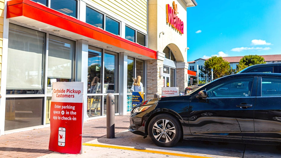 Wawa store with person walking and a car out front.