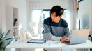 A younger person reviews bills on their desk and inputs them into a computer. - Fox Business News