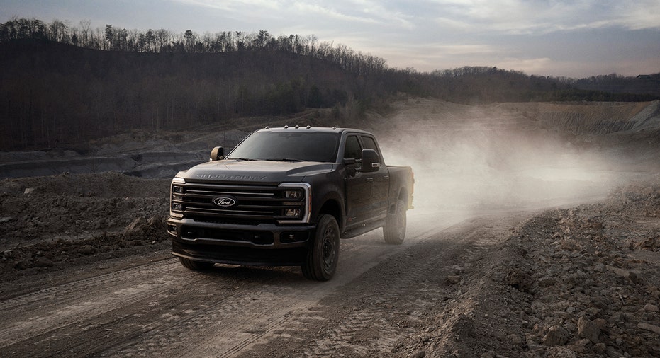 A Ford Super Duty Carhartt edition pickup truck drives along a dirt road