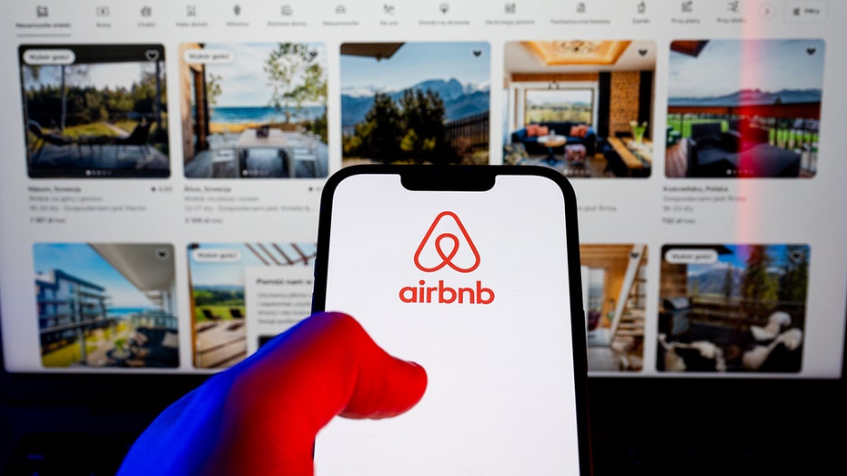 The Airbnb logo is displayed on a smartphone in front of property listings.