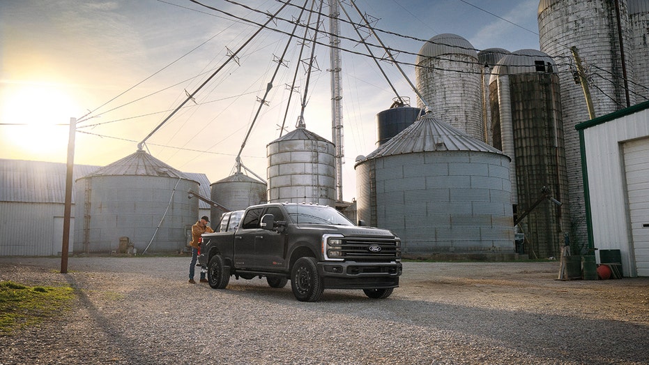A Ford Super Duty Carhartt edition pickup truck is parked near agricultural silos