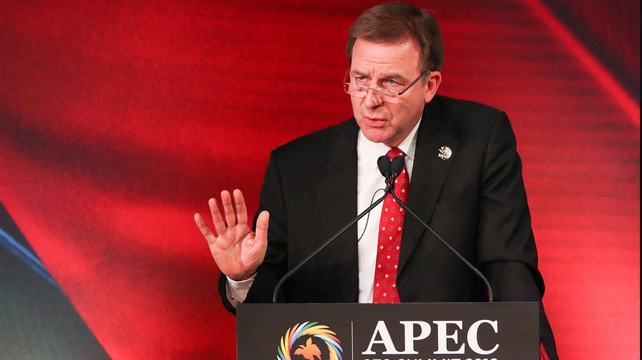 Senior Vice President of ExxonMobil Neil Chapman gestures in front of a bright red background