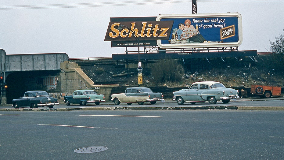Cars driving past a billboard.