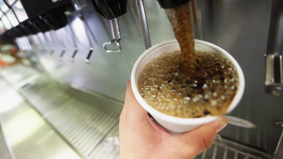 A person is seen filling up a fountain soda.