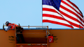 American flag flies behind a construction worker during construction of a new building. - Fox News