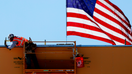 American flag flies behind a construction worker during construction of a new building. - Fox Business News