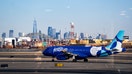 An Airbus A320 plane, operated by JetBlue Airlines at Newark Liberty International Airport (EWK) in front of the skyline of lower Manhattan and One World Trade Center in New York City on Jan. 15, 2026 in Newark, New Jersey.  - Fox Business News