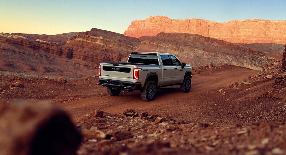 A 2027 Chevrolet Silverado 1500 ZR2 in White Sands is shown on a dirt road in a canyon landscape.