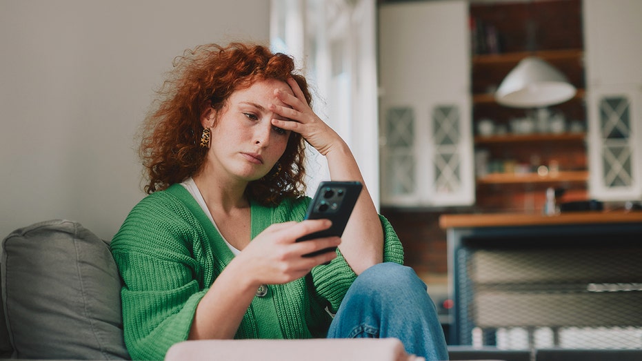 Woman looks at phone stressed