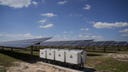 Power inverters sit beside solar panels at a utility-scale solar energy facility