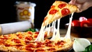 A person pulls a piece of pizza off a dish. - Fox Business News