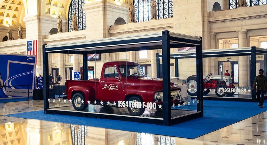 A 1954 Ford F-100 is displayed inside the