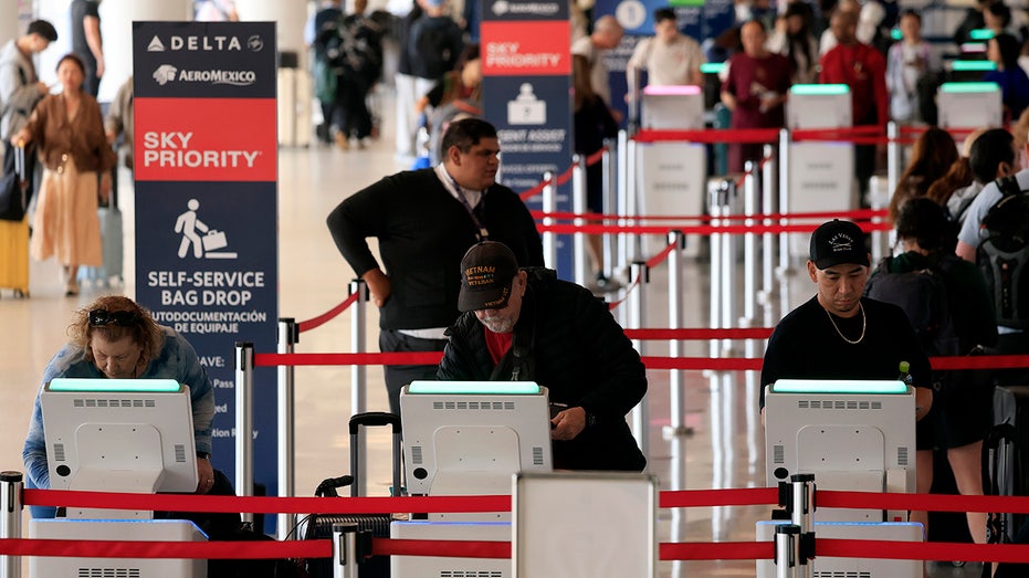 Travelers check in at a Delta Air Lines kiosk
