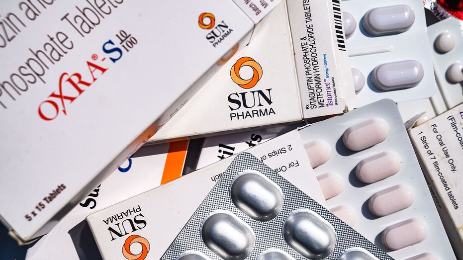 Boxes of generic prescription medications and blister packs of tablets are displayed together