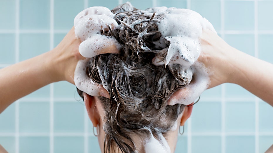A woman shampoos her hair.