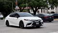 A portrait of a white Toyota Camry sedan traveling down a highway in moderate traffic. - Fox News