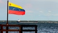 A Venezuelan flag waves in front of oil tanker on lake in Maracaibo, Venezuela on July 27, 2026. The capital of the oil state and surrounding areas offer a stark contrast between Venezuela's oil wealth and the daily reality of communities living near the country's energy infrastructure. While oil continues to generate revenue and crude is shipped through terminals serving international markets, many local residents say they have seen little benefit from the sector. - Fox News