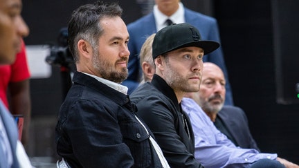 Siblings Joey and Jesse Buss (in black hat), from left, sit in the front row during a press conference announcing new Los Angeles Lakers head coach Darvin Ham at the UCLA Health Training Center in El Segundo, California, on June 6, 2022. - Fox Business News