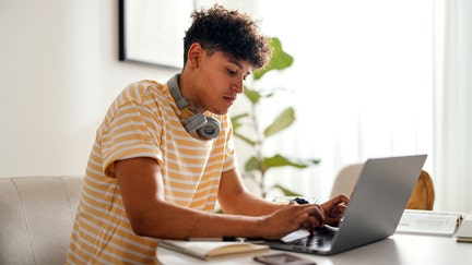 A teenager studies near a computer at his home. - Fox Business News