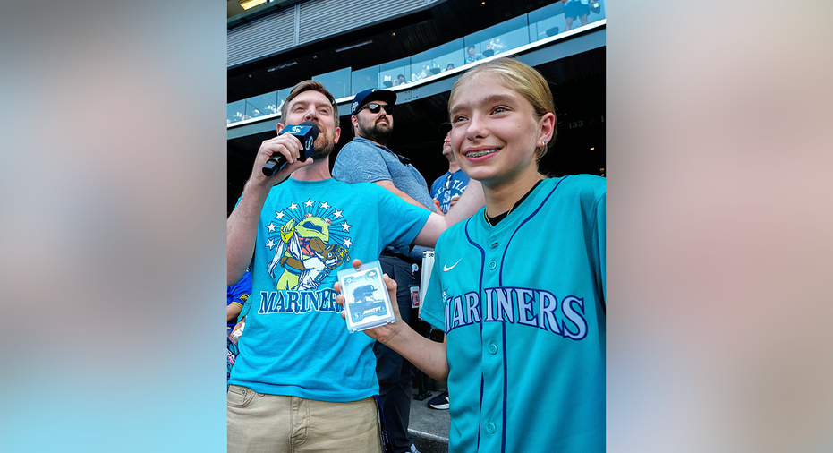 Mariners fan Abby holds her rare Jimothy rookie card after pulling it at T-Mobile Park