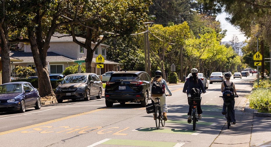 People ride bikes next to cars