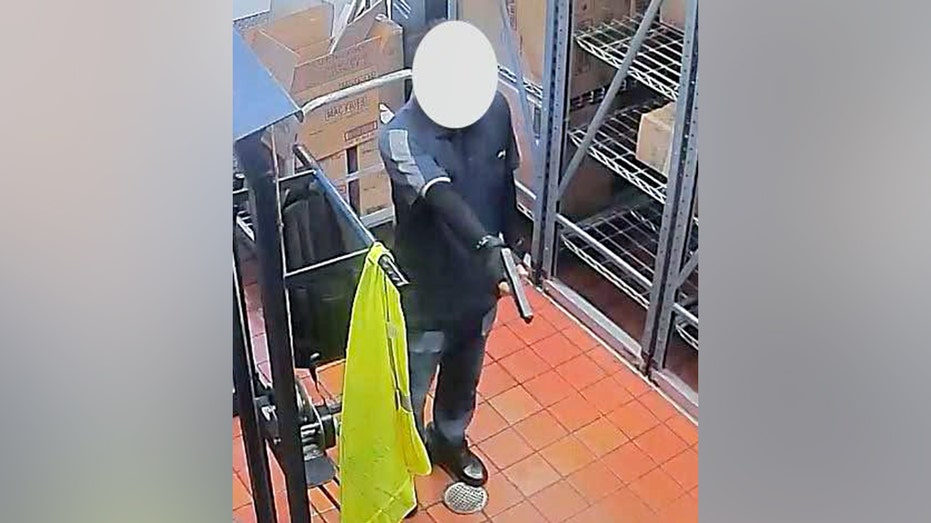 surveillance image showing suspect pointing firearm inside restaurant 