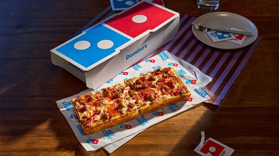 Domino’s new Detroit-style Domino pizza cut into two rectangular slices beside a branded pizza box