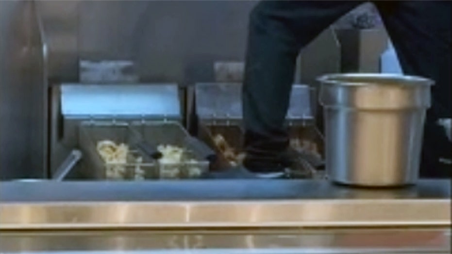 Panda Express worker stands on counter while cleaning frying station