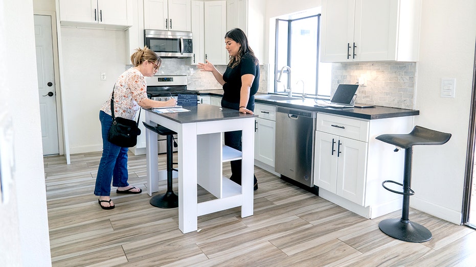 A real estate agent talks with a client in a house.