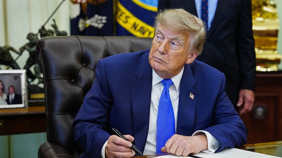 President Donald Trump signs an executive order in the Oval Office at the White House