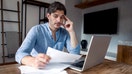 A man looks at bills next to a computer in his home. - Fox Business News