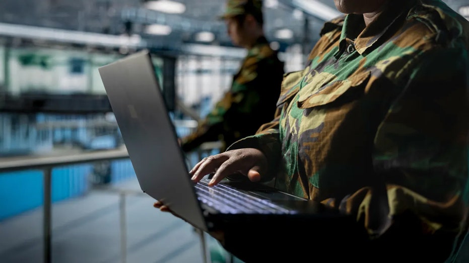 Close up of server hub employee in soldier uniform typing on laptop