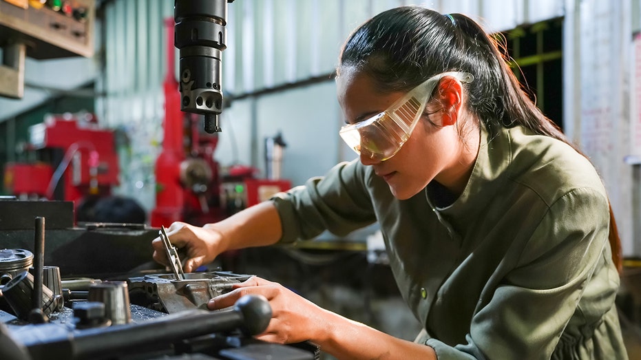 Industrial workshop action female mechanic repairing machinery factory environment close-up view for empowerment