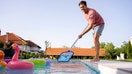 A man cleans the pool in his backyard. - Fox Business News