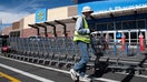 A Walmart employee pushes a line of shopping carts across the pedestrian crosswalk outside the Grocery & Pharmacy entrance canopy of a Walmart retail store in Heber City, Utah, United States, on October 2, 2026. - Fox Business News